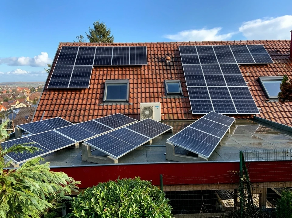 Ouvrier en équipement de protection individuelle avec casque jaune et harnais de sécurité travaillant sur installation de panneaux solaires photovoltaïques